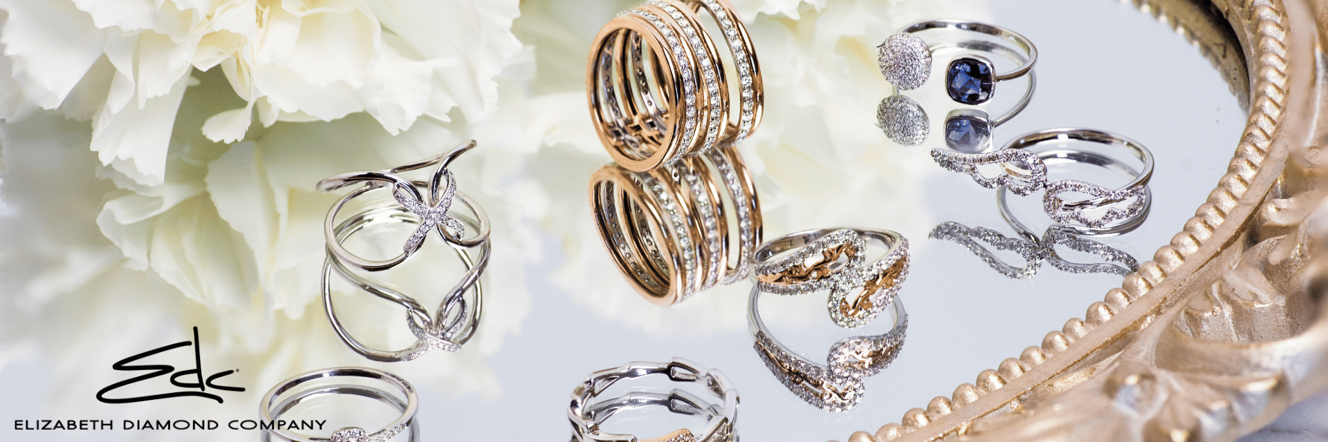 Custom Jewelers Centerville, Ohio - banner image showing an assortment of rings on a mirrored tray