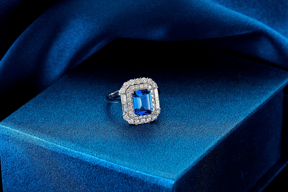 Custom Jewelry Design Centerville, Ohio - a ring with a blue gemstone surrounded by diamonds on a blue background