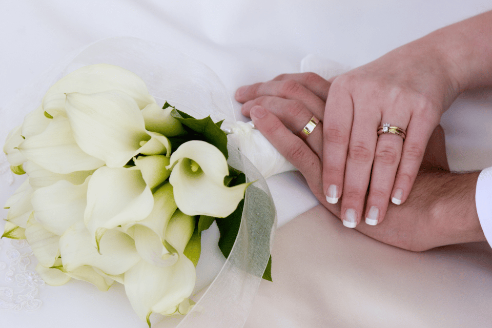 Custom Men's and Ladies Matching Wedding Bands Dayton, OH - couple's hands holding a bouquet of calla lilies 
